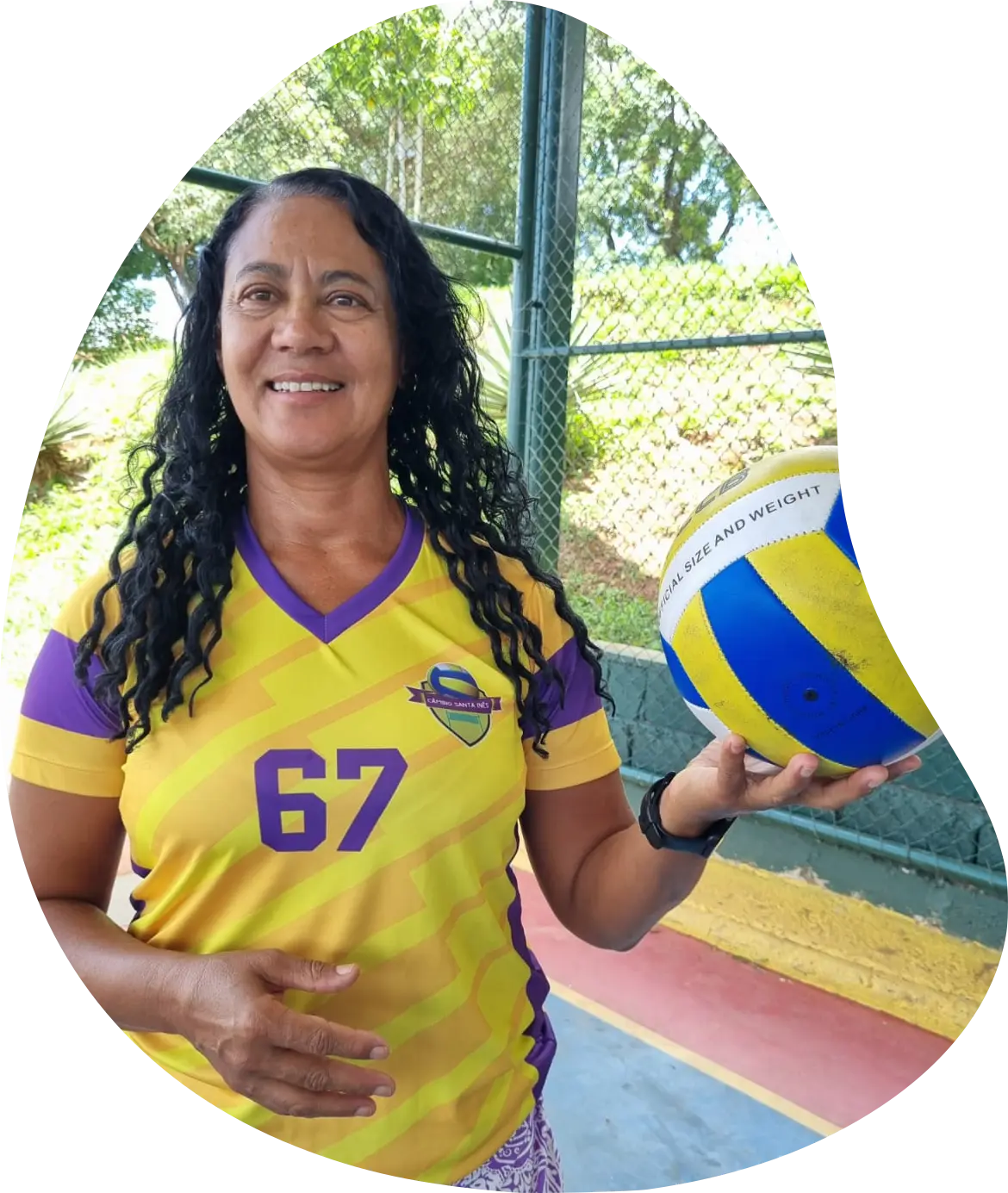 Pessoa com camisa amarela segurando uma bola de volei.